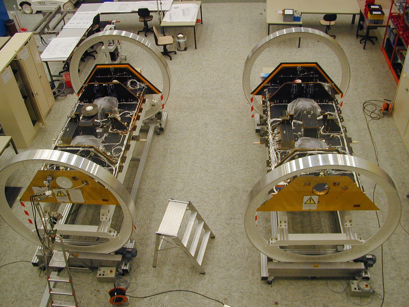 The GRACE satellites are shown without solar panels during component integration in a German clean room.